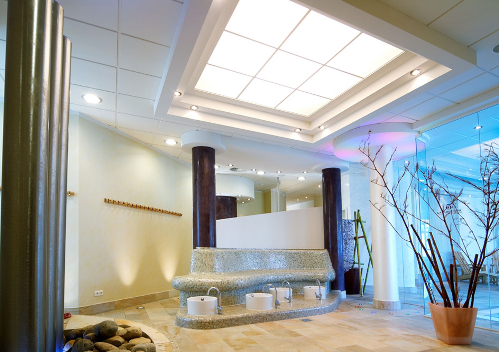 Ein hochwertig gestalteter Spa-Bereich mit modernen Akustikdecken, stilvollen Säulen und einer gemütlichen Fußbadzone.